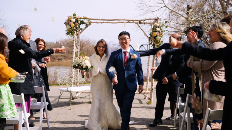 Newlyweds walking down the aisle as guests toss petals