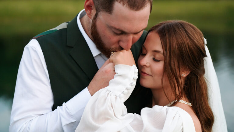 Groom kissing bride’s hand during wedding portrait.