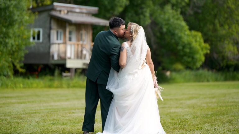Bride and groom kissing outdoors.