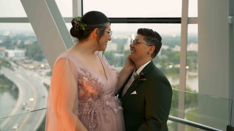 Wedding couple portrait inside a modern venue with city views through large windows