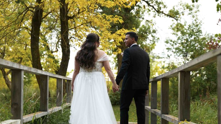 Bride and groom holding hands on a wooden bridge during an outdoor wedding
