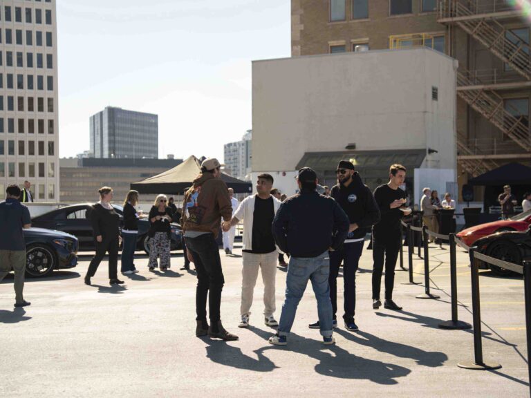 People networking at an outdoor city event with cars and urban buildings for a promotional video