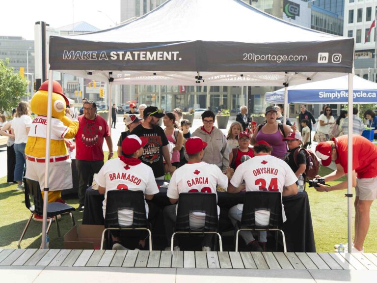 Baseball players signing autographs for fans at an outdoor community event