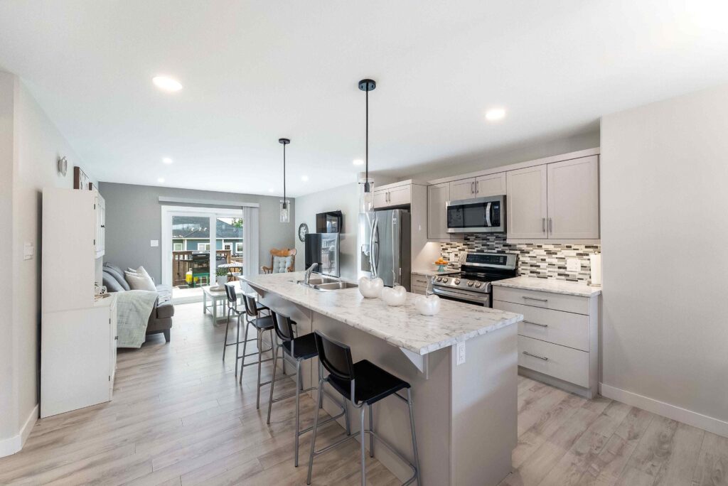 Open-concept kitchen with marble island, bar seating, and bright living area