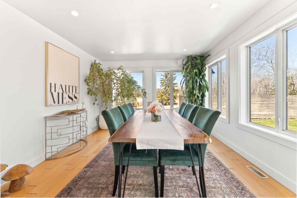 Bright dining room interior with large windows and green chairs for a real estate listing