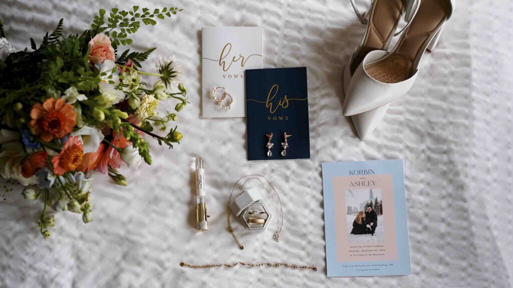 Wedding flat lay with vow books, bouquet, rings, shoes, and invitation for a Manitoba wedding