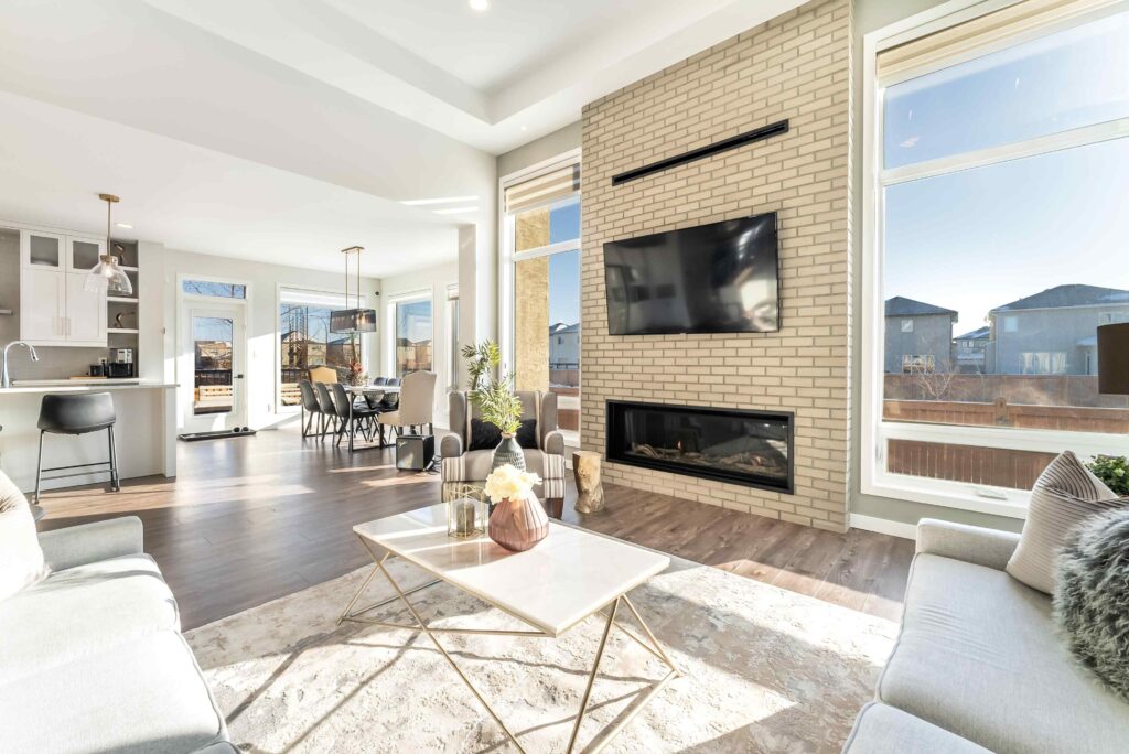 Modern living room with brick fireplace, mounted TV, and open kitchen