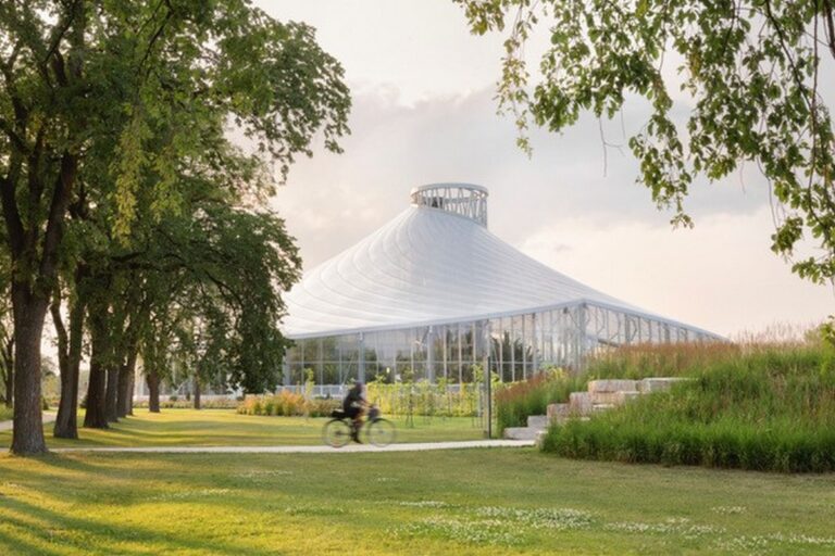 The Leaf at Assiniboine Park with green lawn, trees, and cyclist