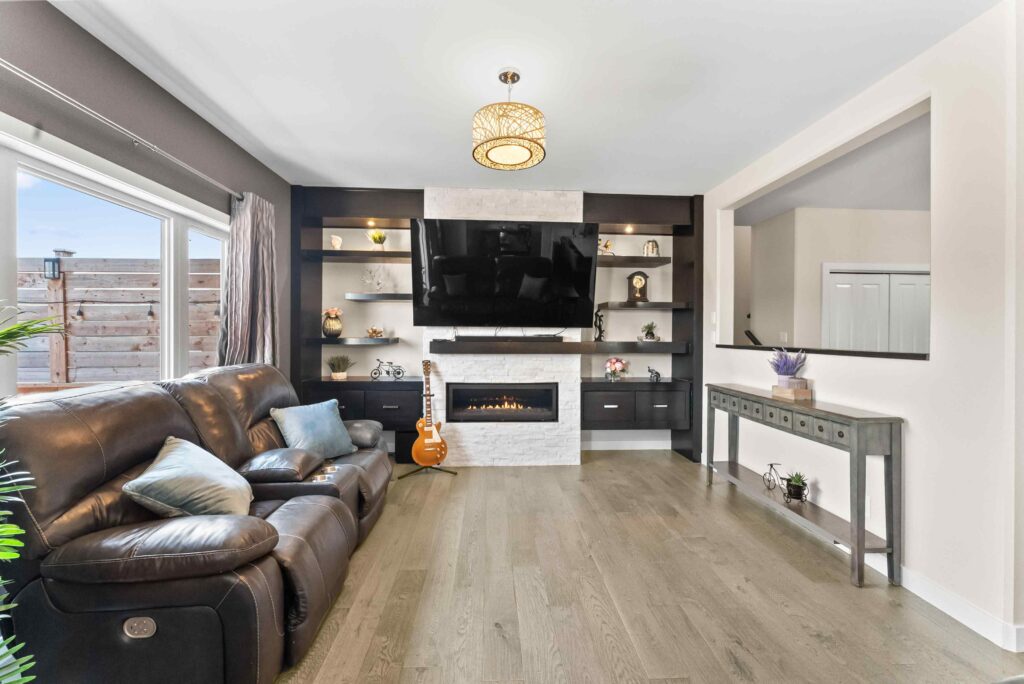 Modern living room interior with fireplace, built-in shelves, and large window for real estate listing
